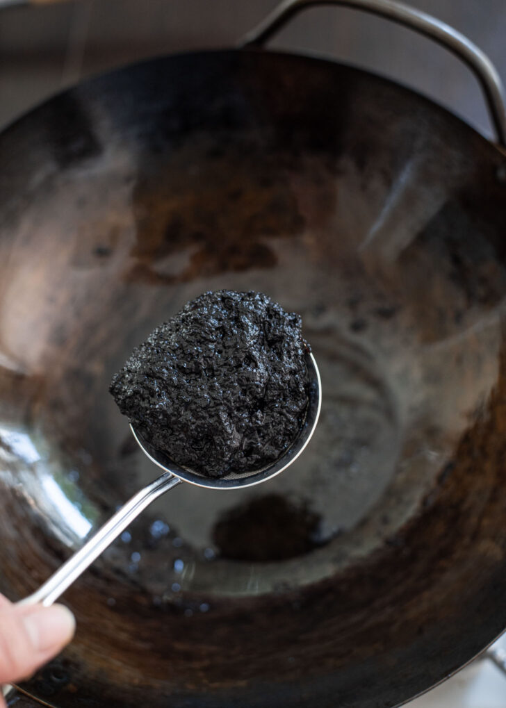 A small strainer draining the oil off the fried black bean paste.