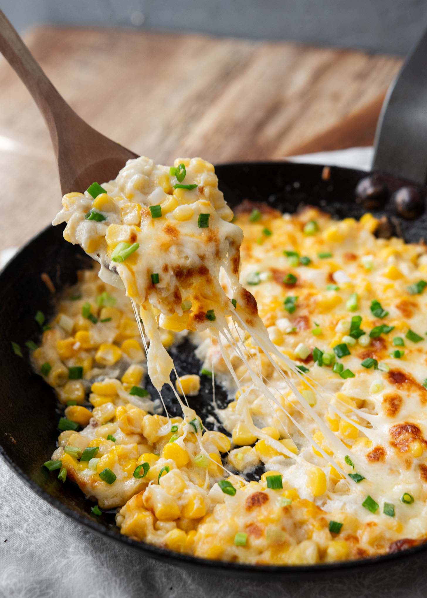 A spoonful of corn cheese with stretchy melted cheese. 