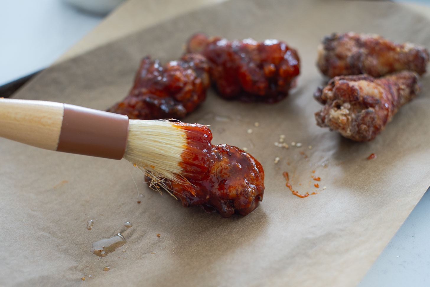 Brushing gochujang glaze to crispy chicken wings.