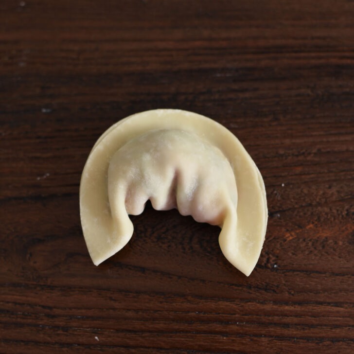 Both ends of dumpling wrapper are bend down toward the center.
