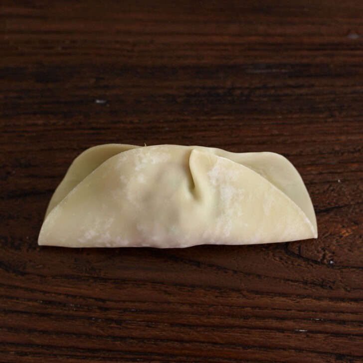 Mandu wrapper with filling inside folded in half.