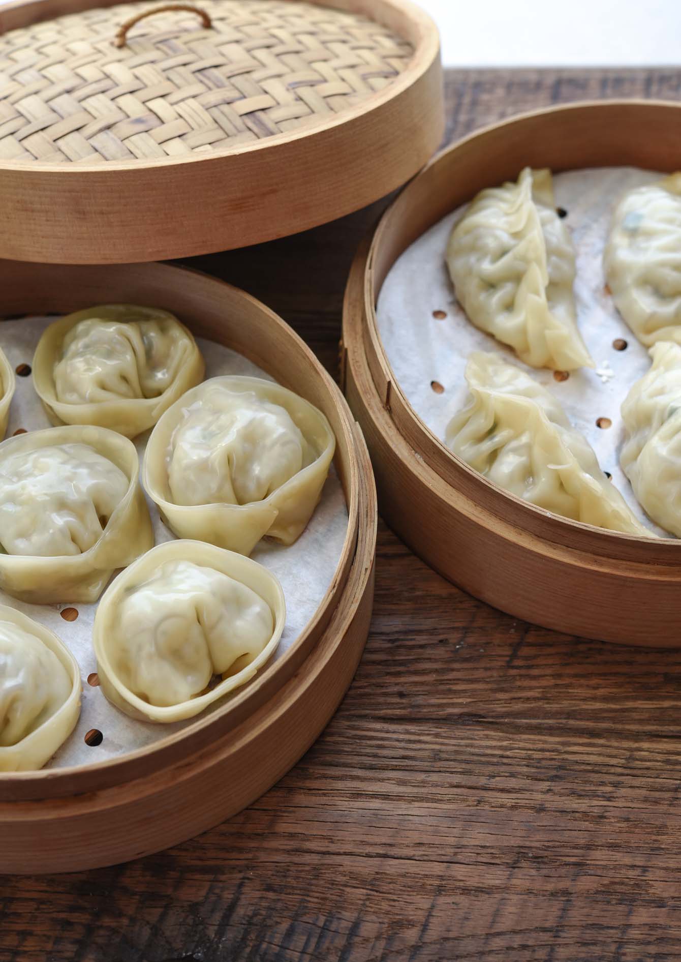 Two different shapes of Korean mandu dumplings in bamboo steamer.