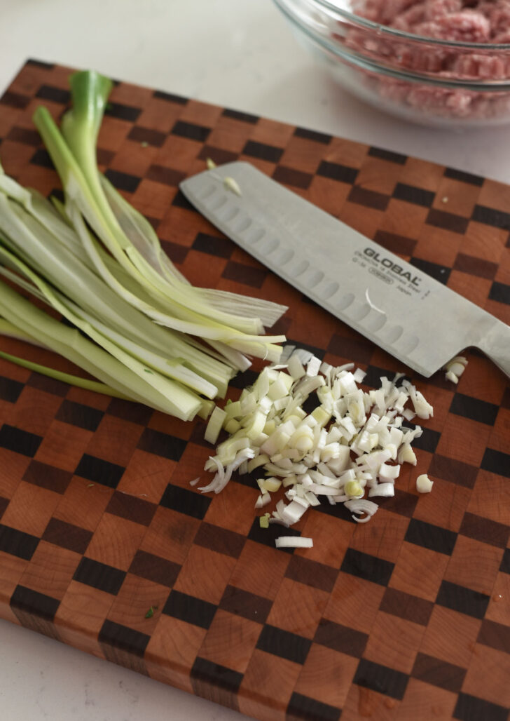 Asian leeks finely chopped on the cutting board.