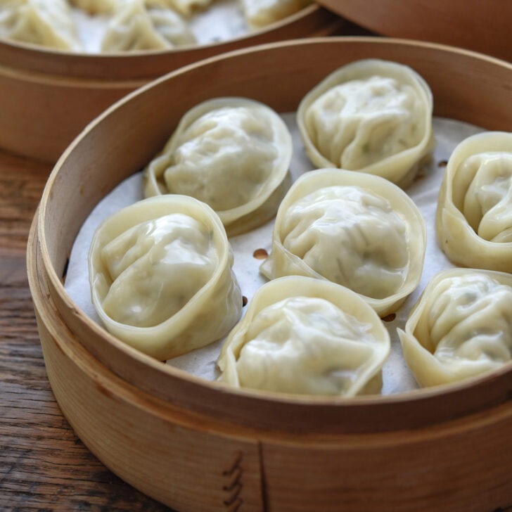 Mandu (Korean dumplings) steamed in a lined bamboo steamer.