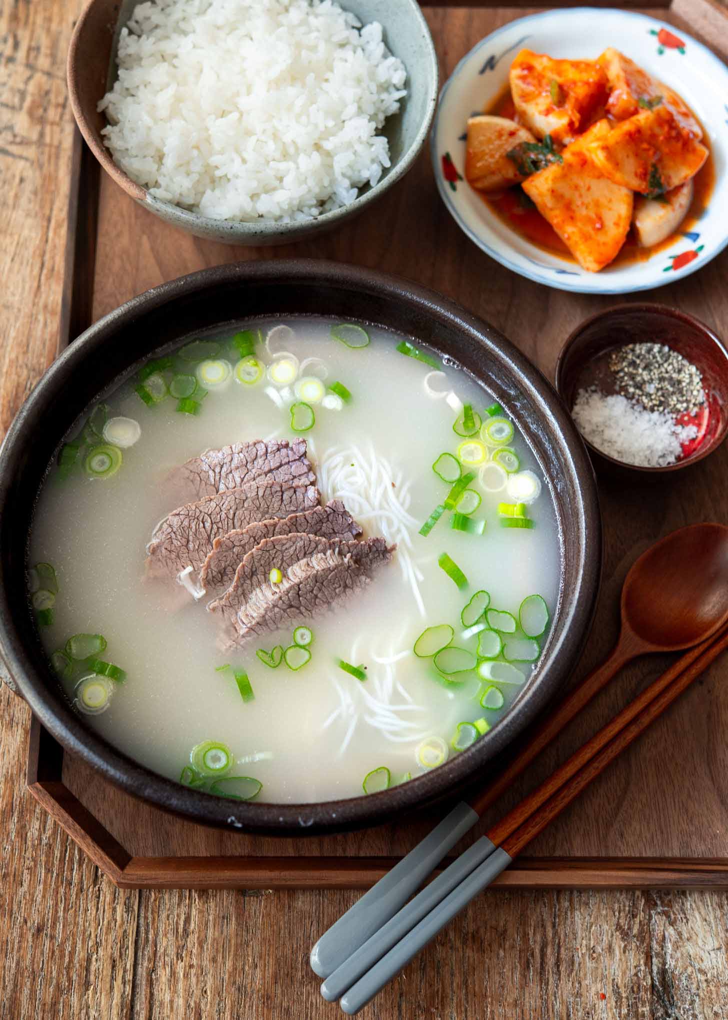 A bowl of seolleongtang, Korean ox bone soup, served with rice and kimchi.