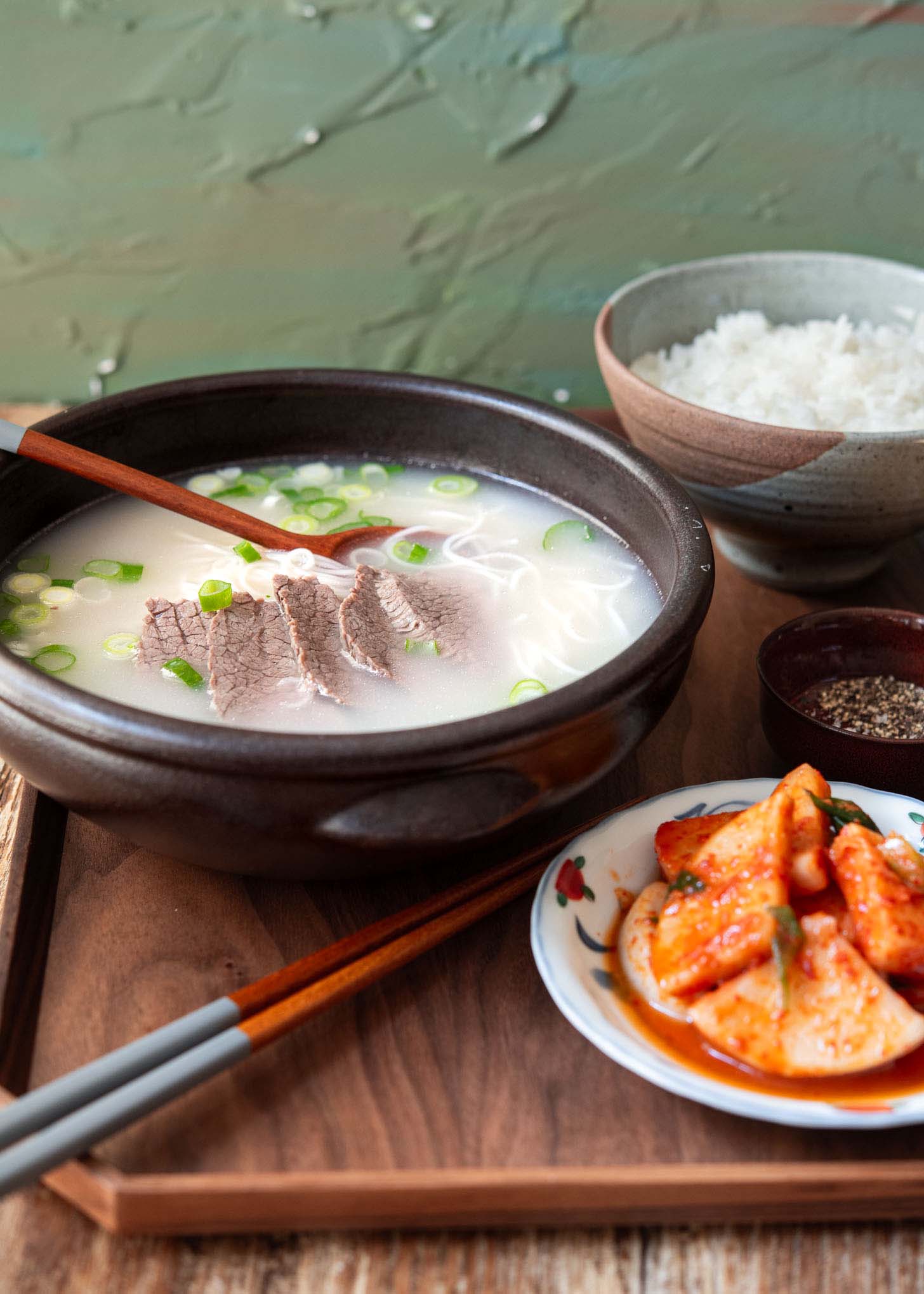 A bowl of Korean beef bone soup (seolleongtang) with rice and radish kimchi.