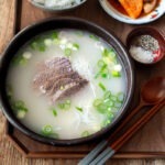 A bowl of seolleongtang with rice and radish kimchi.