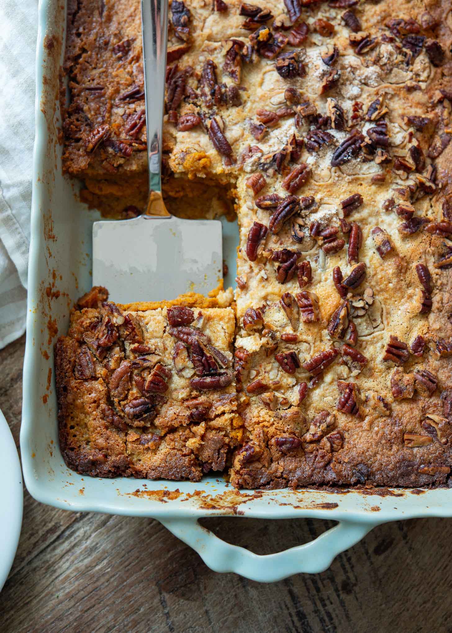 Pumpkin pie crunch with a serving spatula in a pan.