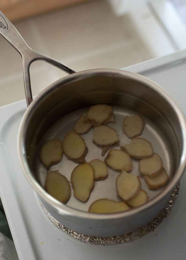 Ginger slices simmering in a pot of water.