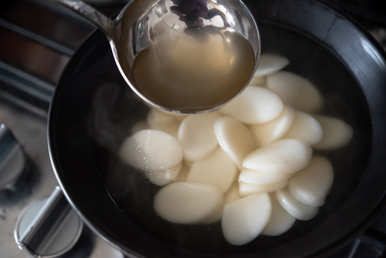 Beef broth poured on a bowl of boiled rice cakes.