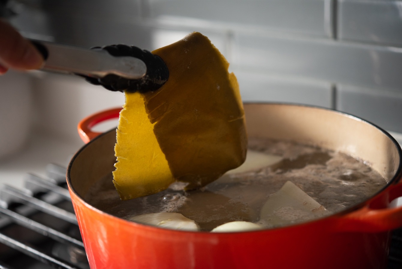 Sea kelp removed from beef broth in a pot.