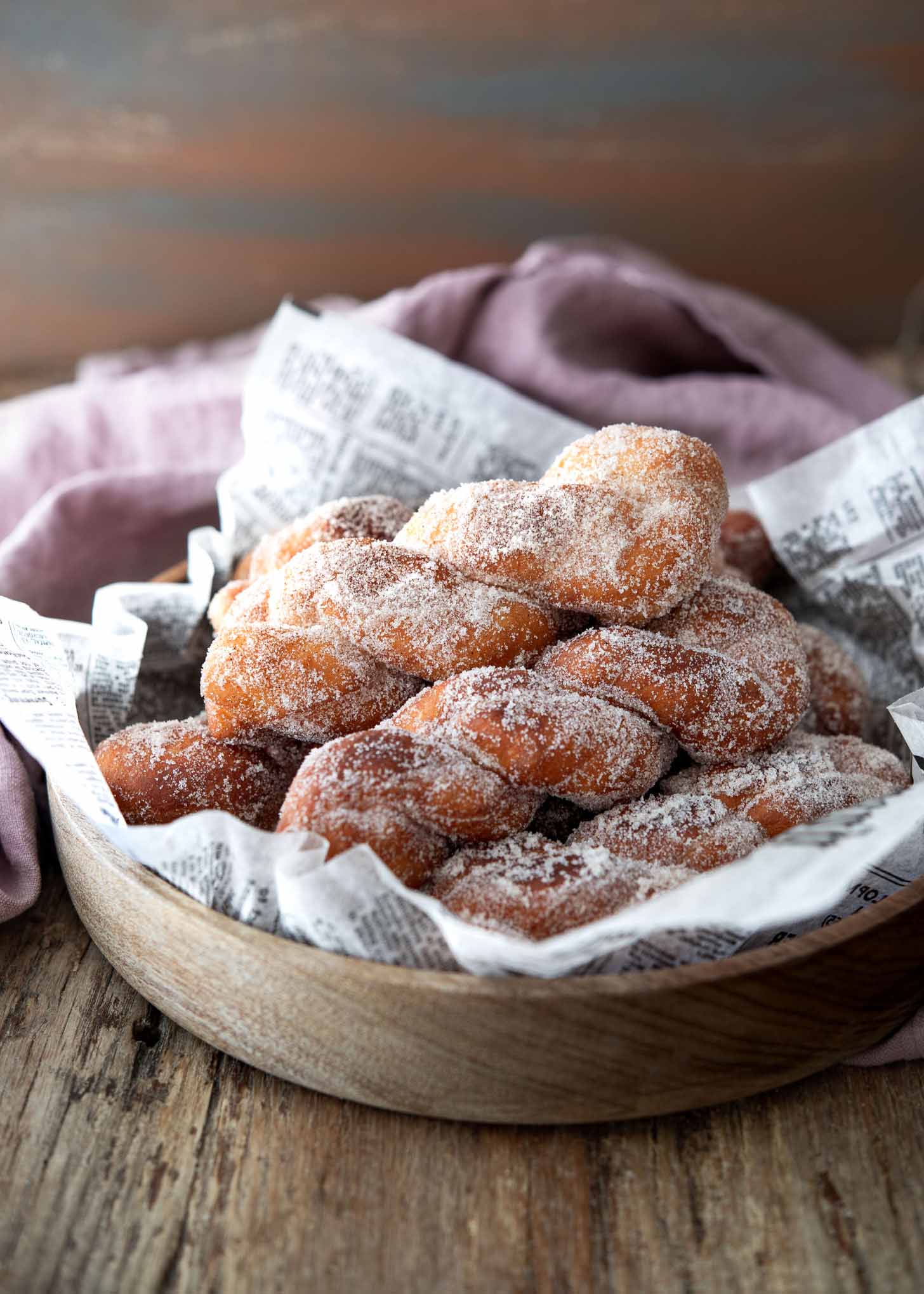 Twisted donut coated with sugar in a serving bowl.