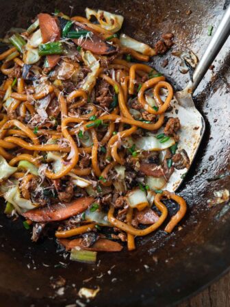 Stir-fried yaki udon noodles with pork and vegetables in a wok.