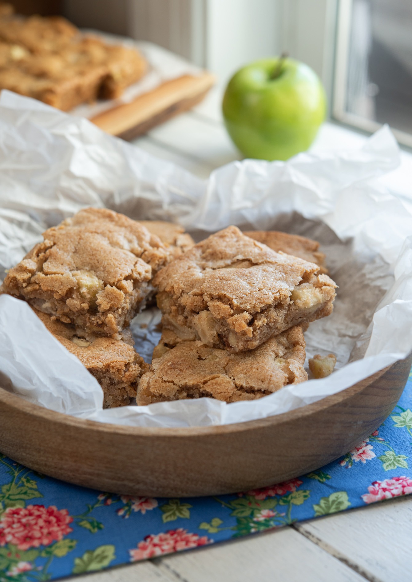 Apple brownie slices served in a parchment paper lined bowl.