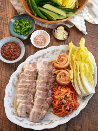 Korean bossam arranged in a platter with cabbage leaves, and radish salad.