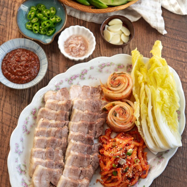 Korean bossam arranged in a platter with cabbage leaves, and radish salad.