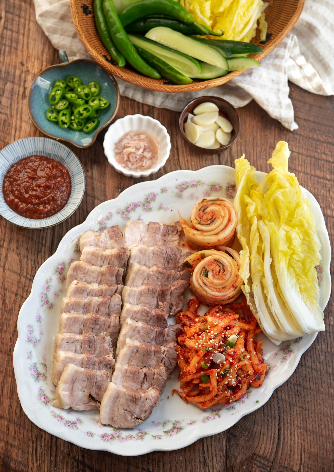 Korean bossam arranged in a platter with cabbage leaves, and radish salad.