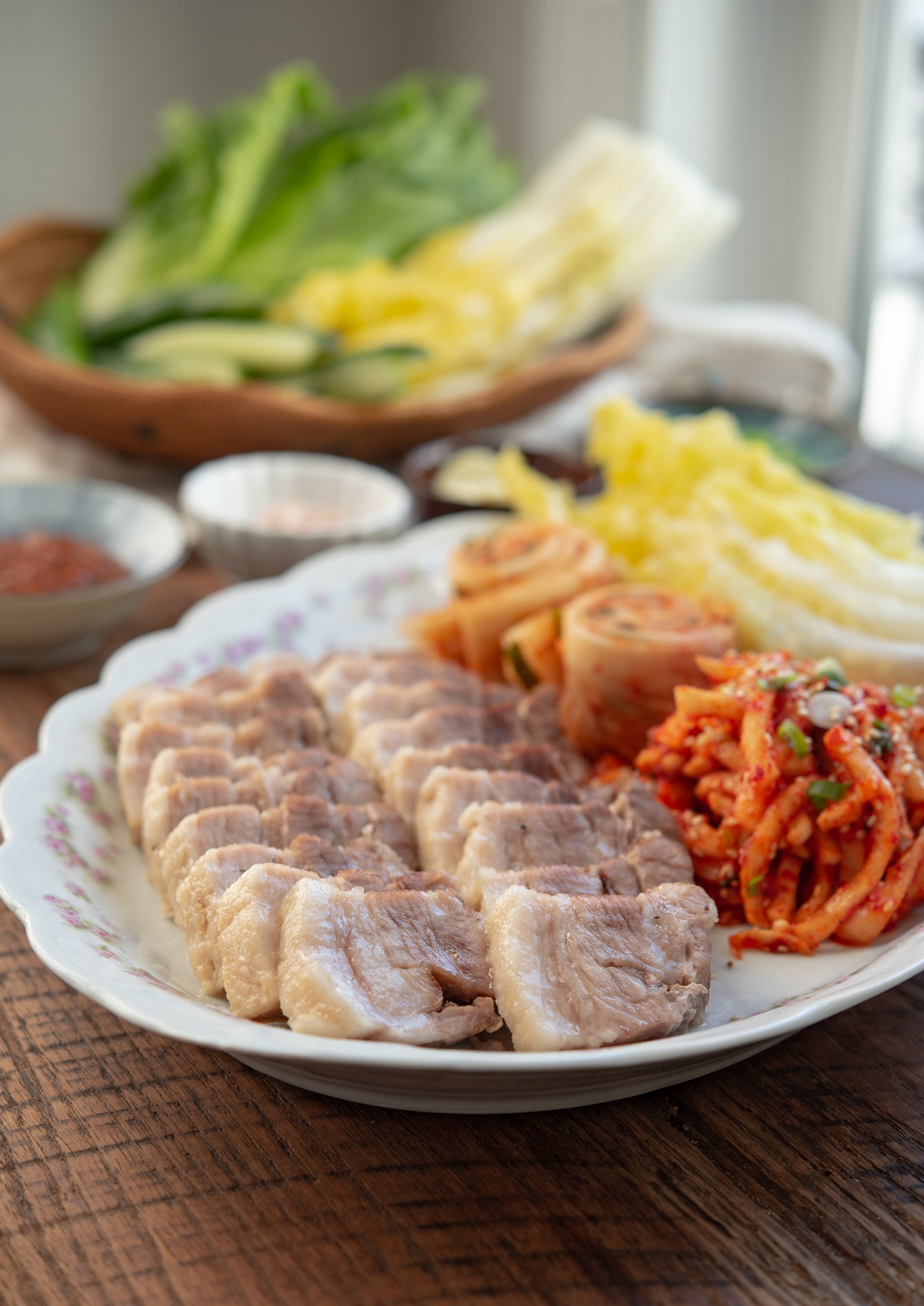 Korean bossam platter filled with pork belly, leaves, radish kimchi.
