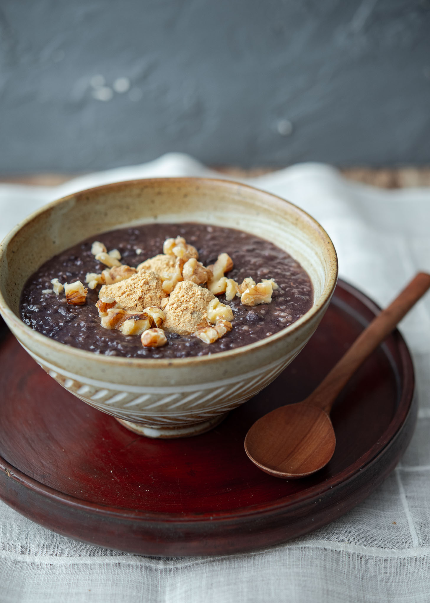 A bowl of danpatjuk garnished with injeolmi and walnut.