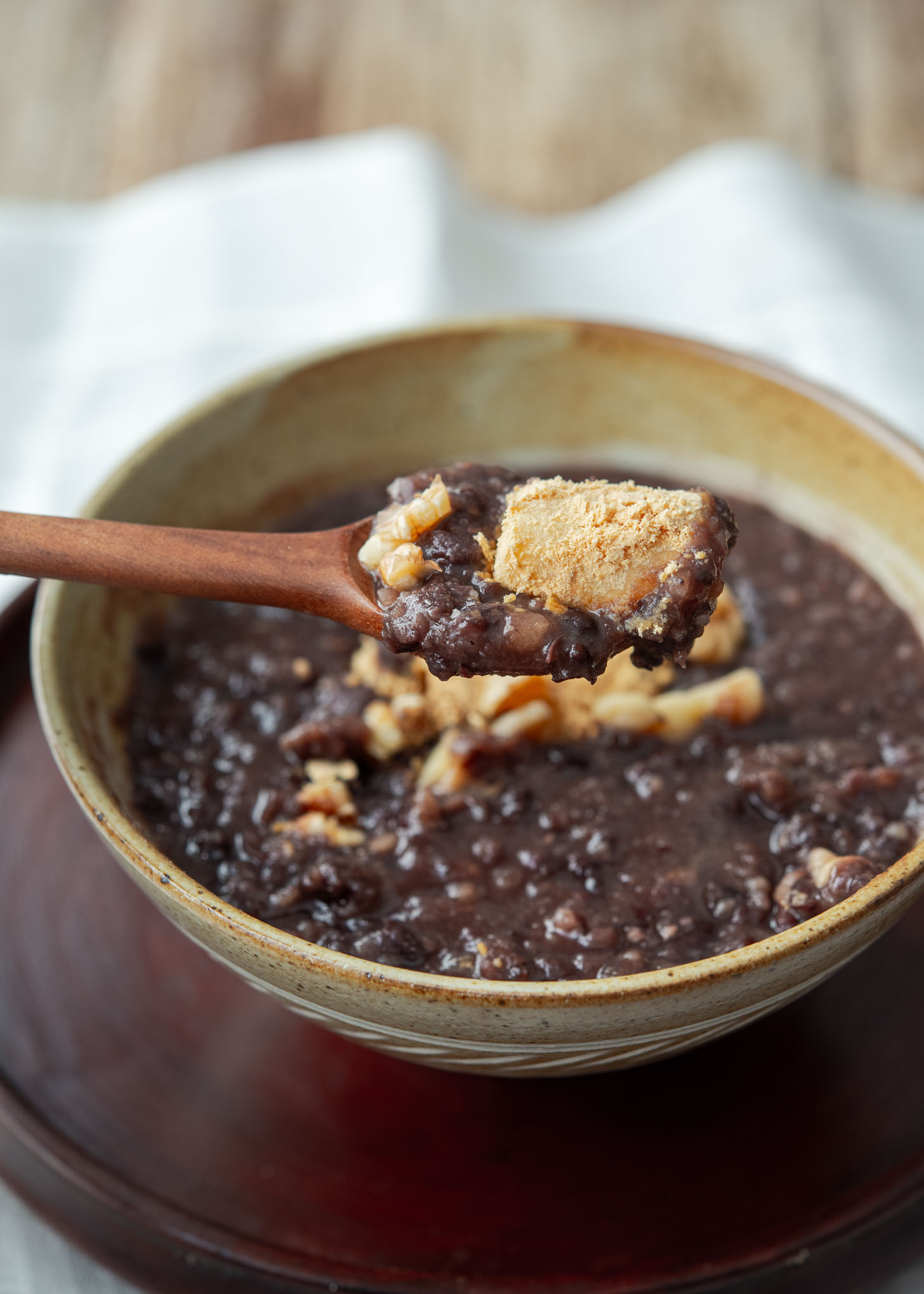 A spoonful of Korean sweet red bean soup with injeolmi garnish.