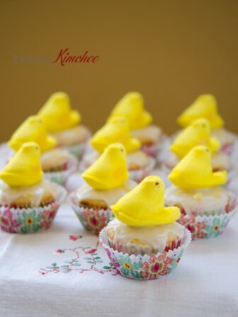 Yellow marshmallow peeps sitting on lemon yogurt cupcakes.