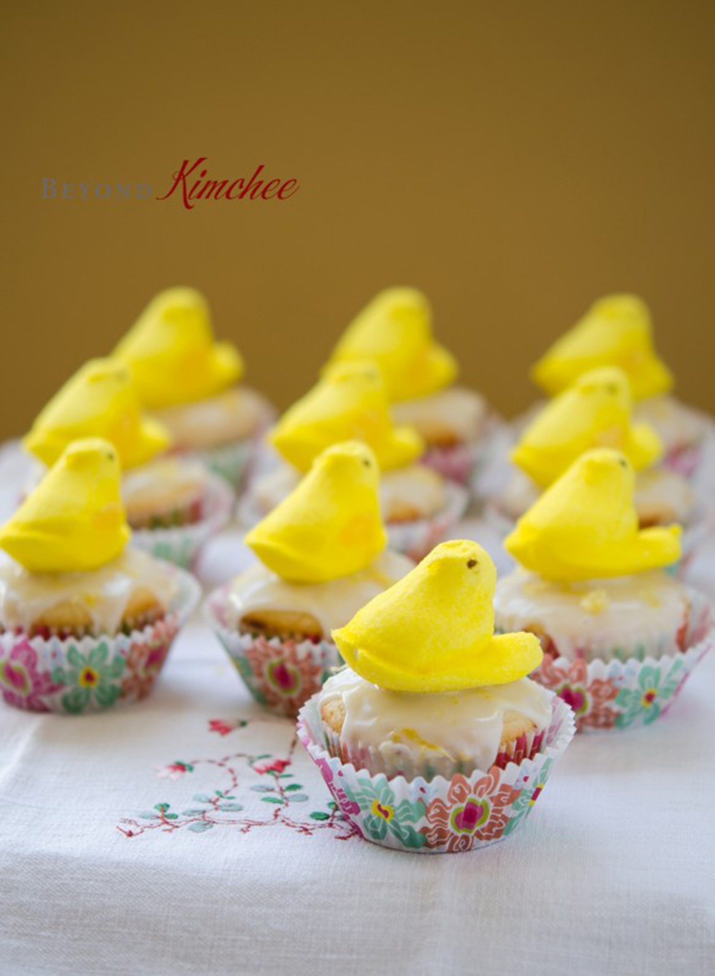 Yellow marshmallow peeps sitting on lemon yogurt cupcakes.