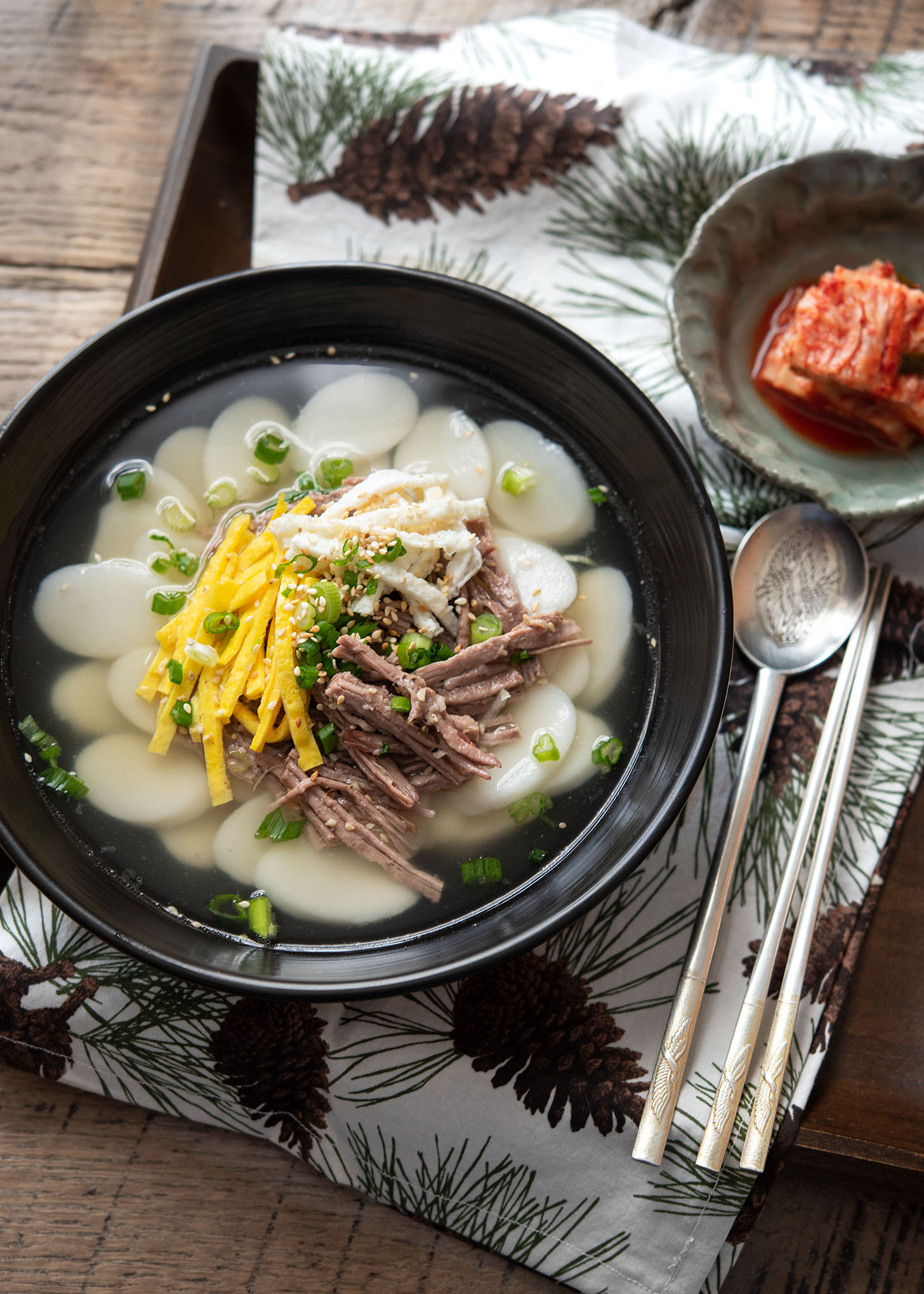 A bowl of tteokguk garnished with beef and egg.