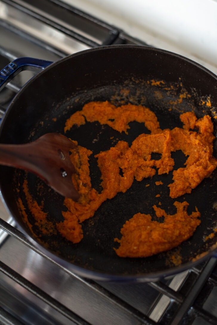 Cooking chili paste before adding coconut milk and vegetables.