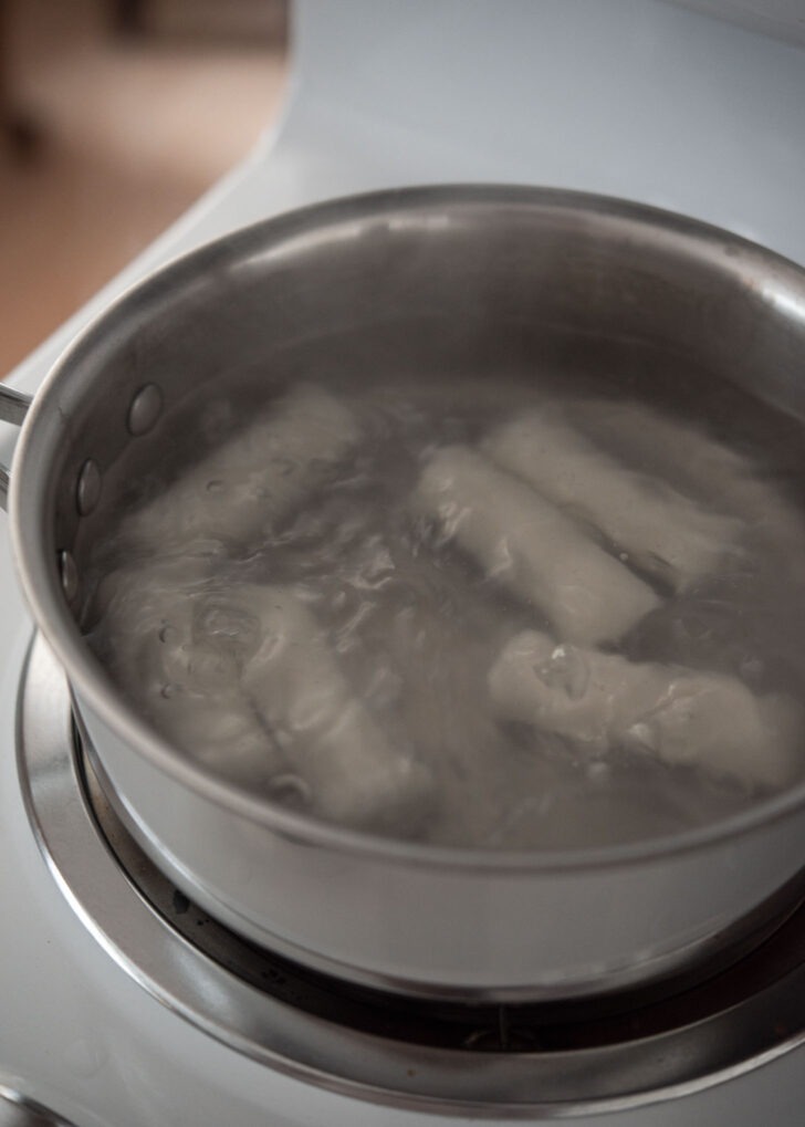 Boiling rice cake logs in a simmering water.