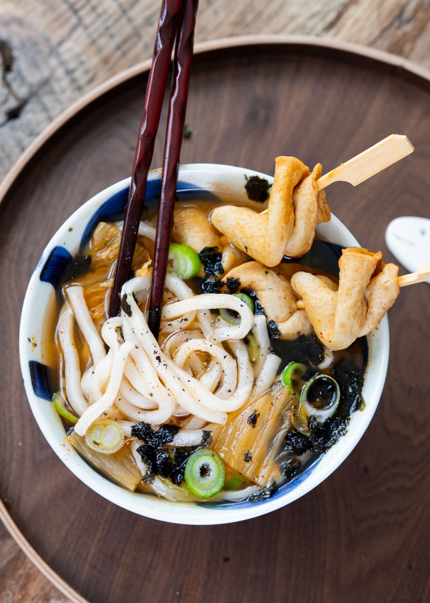 Udon noodles in kimchi dashi broth with fish cakes in a bowl.