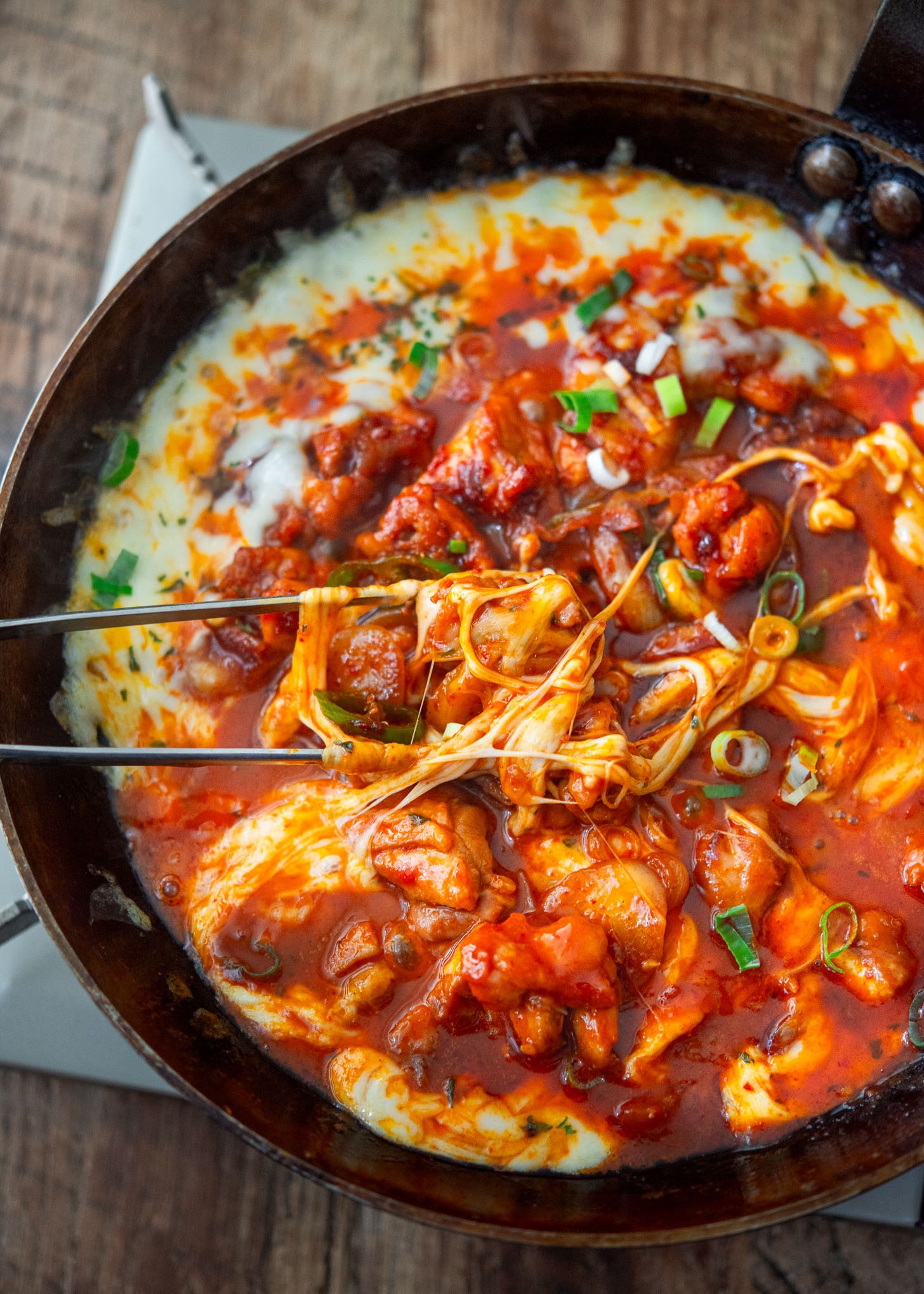 Korean fire chicken (buldak) with melted cheese in a skillet.