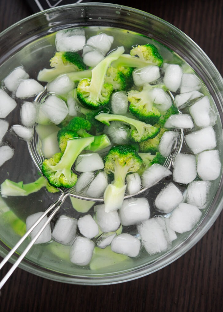 Blanched broccoli florets cooling in ice bath.