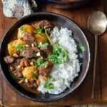 A bowl of beef massaman curry with rice.