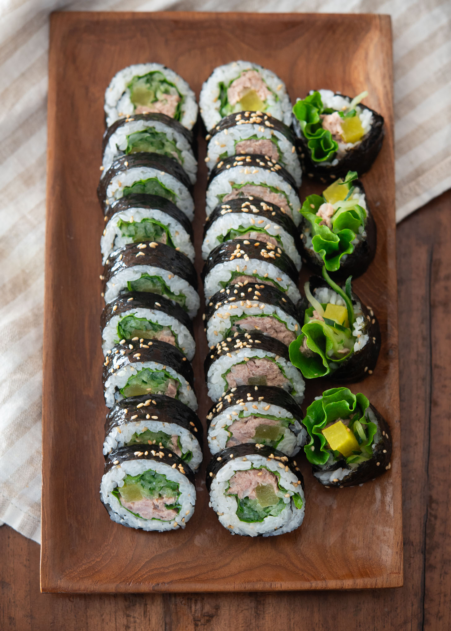 Two rows of sliced cucumber tuna kimbap arranged on a platter.
