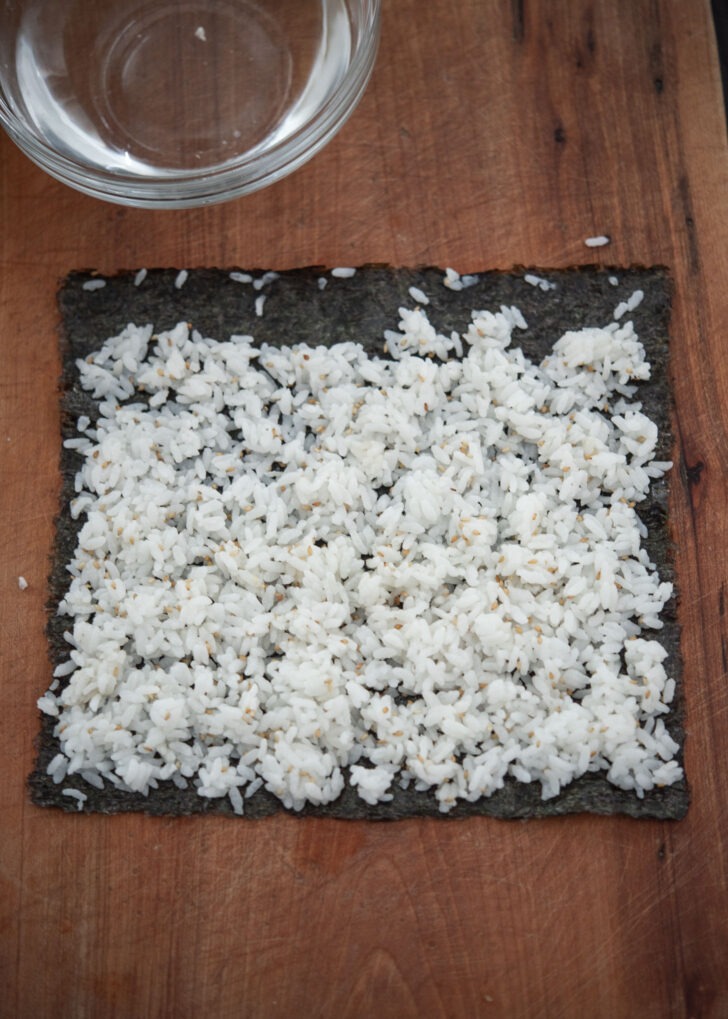 Rice evenly spread on a seaweed sheet.