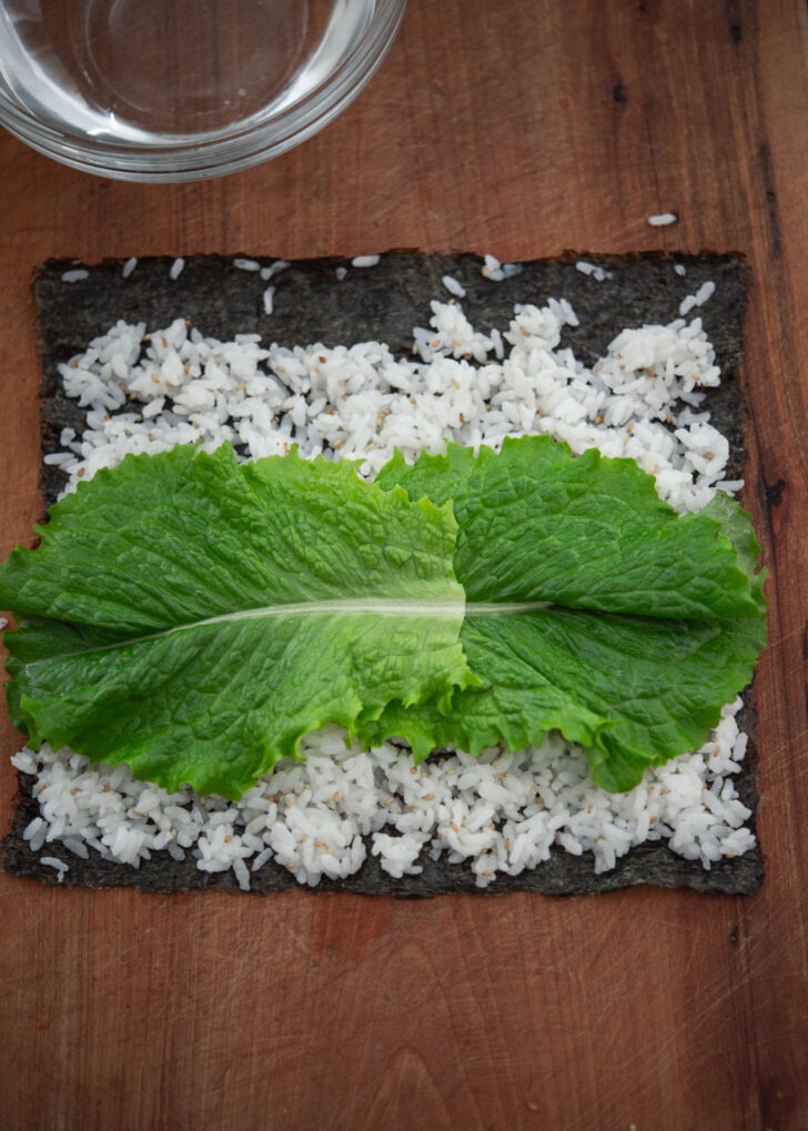 Two lettuce placed on top of rice over seaweed.