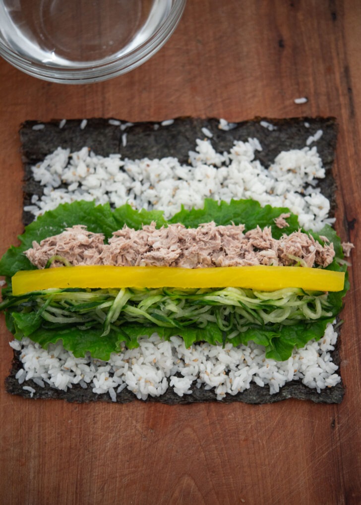 Tuna, cucumber, and radish pickled placed on top of lettuce for kimbap.