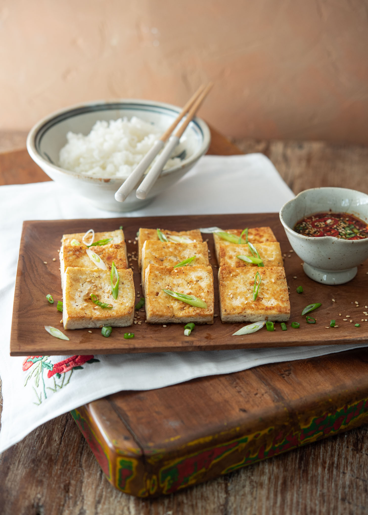 Korean pan-fried tofu and dipping sauce served on a platter.