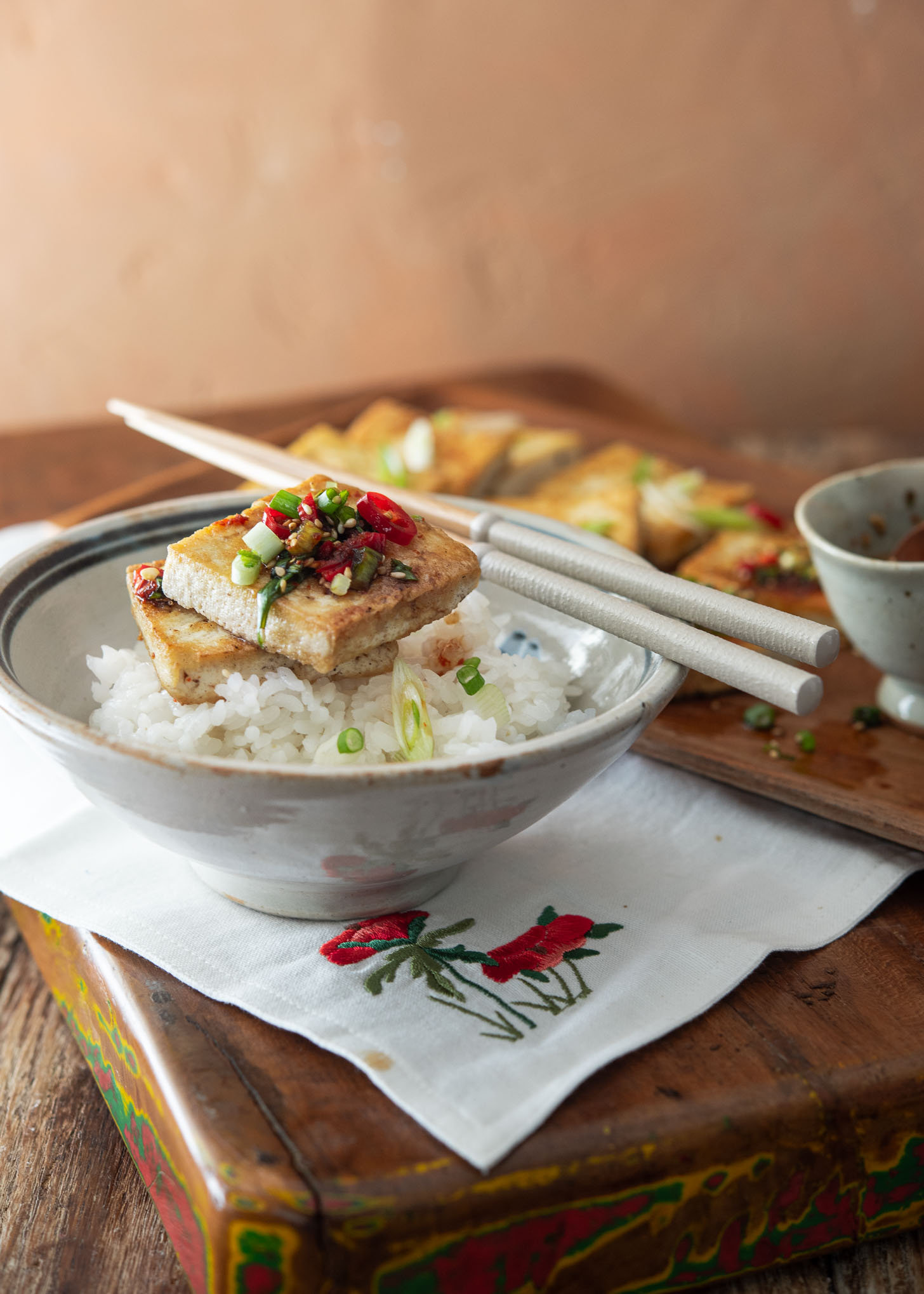 Crispy tofu slices topped with sauce served over rice.