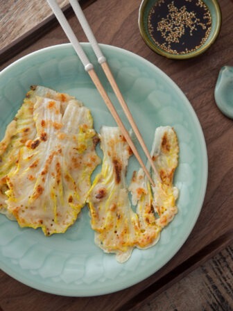 Korean cabbage pancake with chopsticks on a plate.