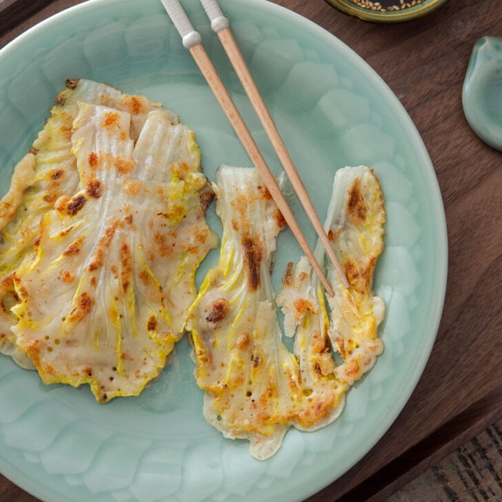 Korean cabbage pancake with chopsticks on a plate.