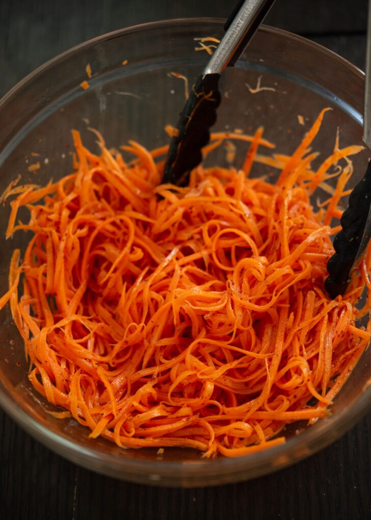 Gochugaru added to the carrot mixture in a bowl.