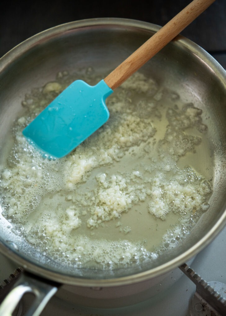 Garlic frying in oil in a skillet.