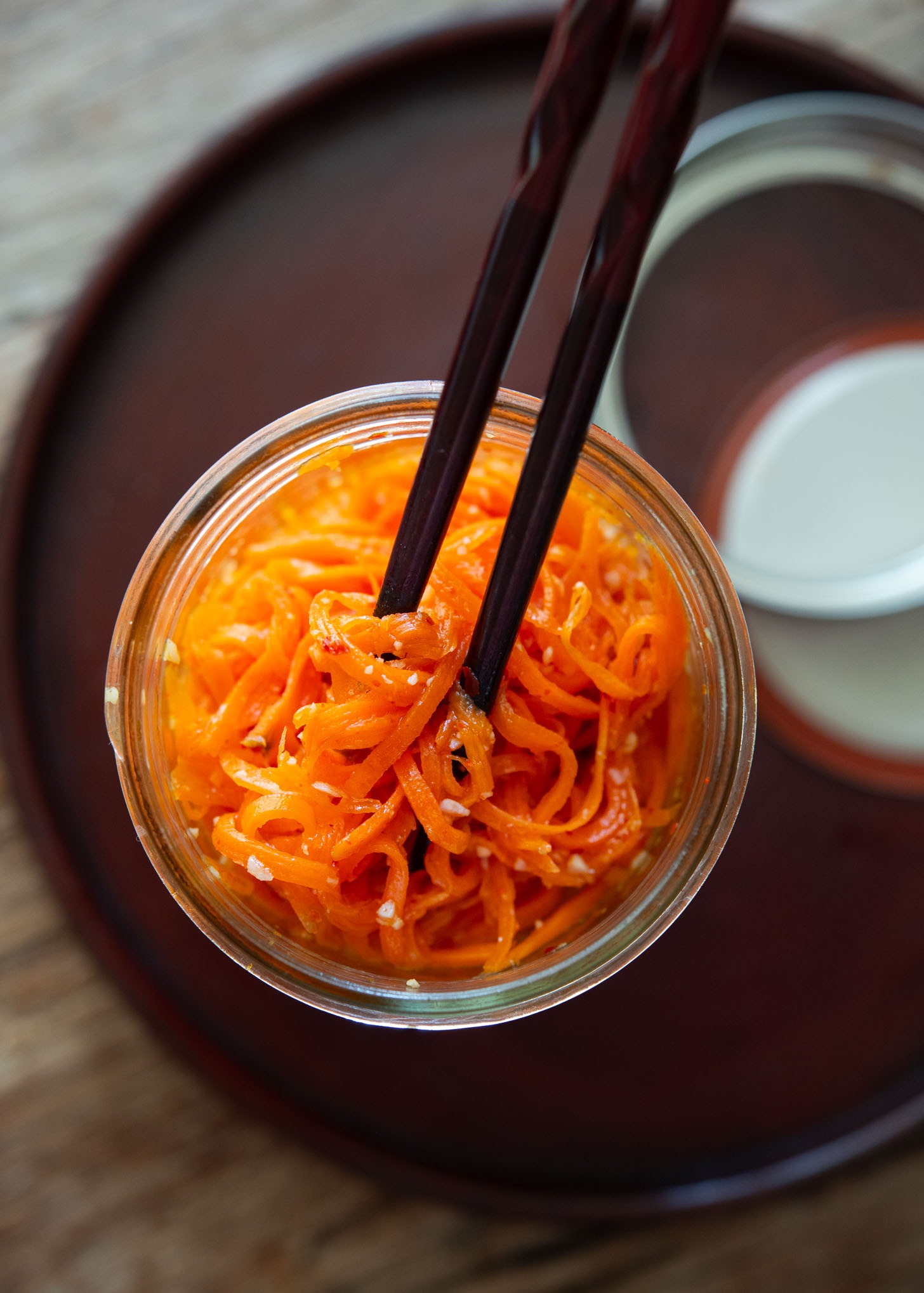 Korean carrot salad in a jar with chopsticks.