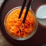 Korean carrot salad in a jar with chopsticks.