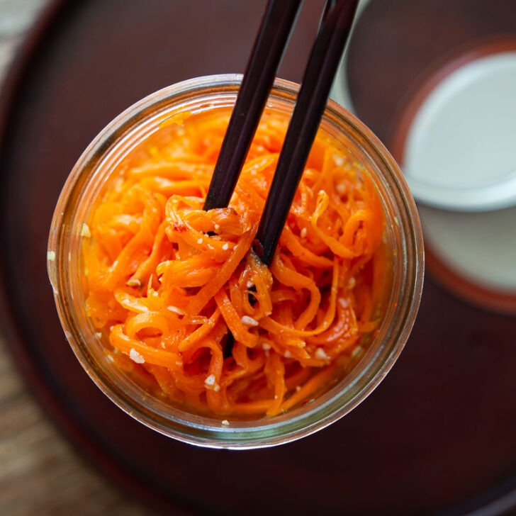 Korean carrot salad in a jar with chopsticks.