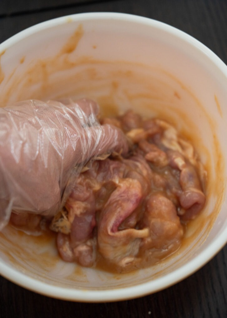 Coating chicken thighs with miso marinade.