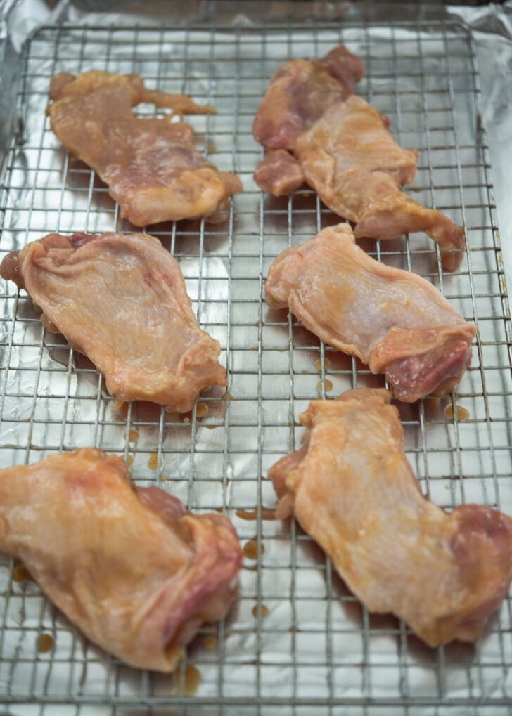 Chicken thighs on the cookie rack over sheet pan.