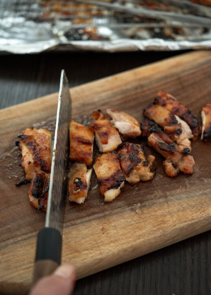 Slicing miso chicken thighs into bite size pieces.