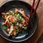 A plate of miso chicken thighs with chopsticks.